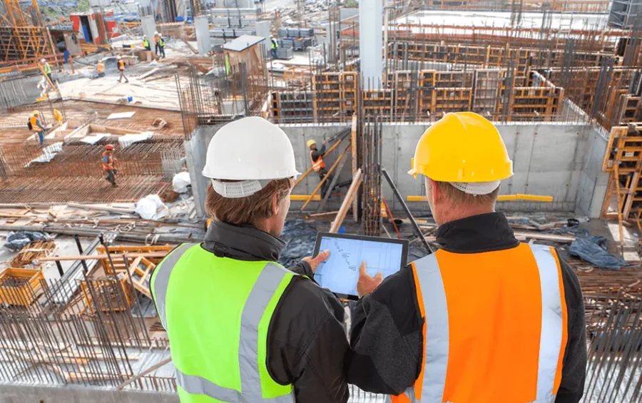 Dois engenheiros conferindo o projeto em tablet no canteiro de obras
